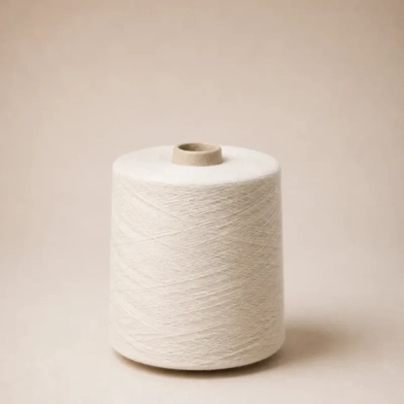 Cuộn sợi cotton open-end 100% màu trắng Cuộn sợi cotton open-end 100% màu trắng đặt thẳng trên nền be