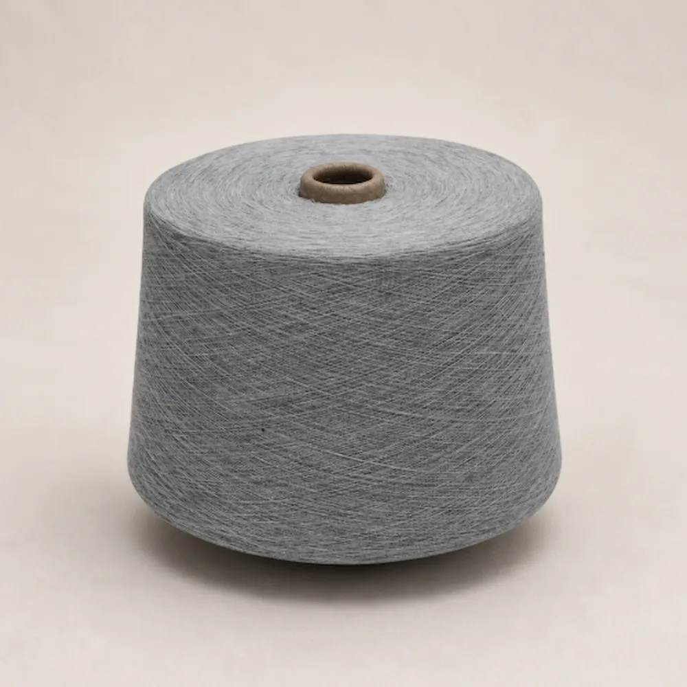 Cuộn sợi melange cotton ring spun màu xám đặt đứng trên nền sáng
