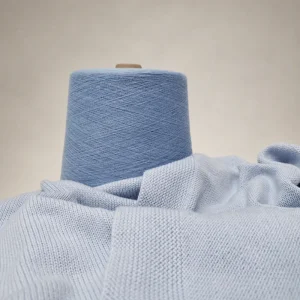 Sợi Cotton Nhuộm Màu 40S1 Xanh Nhạt Cone sợi cotton nhuộm màu 40S/1 xanh nhạt đặt cạnh vải dệt kim