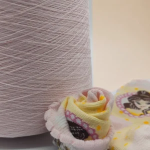Sợi cotton mercerized JC60S1 cho tất dệt kim Cận cảnh cone sợi cotton mercerized màu hồng nhạt cạnh các mẫu tất dệt kim