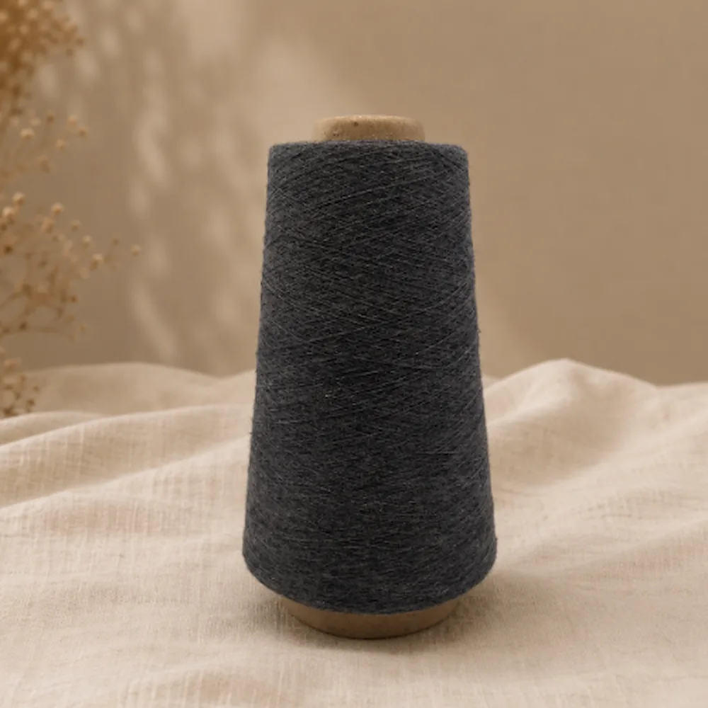 Một cone sợi cotton màu xám đậm dựng đứng trên nền vải sáng