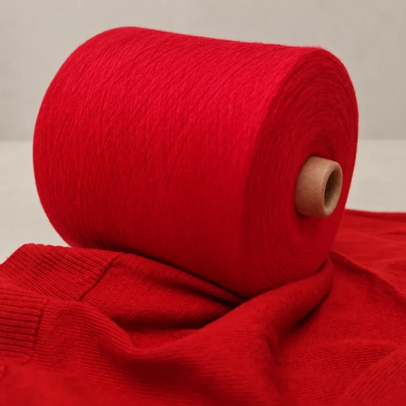 Cone sợi cotton đỏ đặt nghiêng cạnh mẫu dệt đỏ