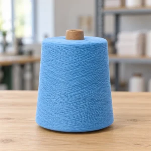 Cone sợi cotton mercerized 80S/2 màu xanh nhạt đặt đứng trên mặt gỗ.
