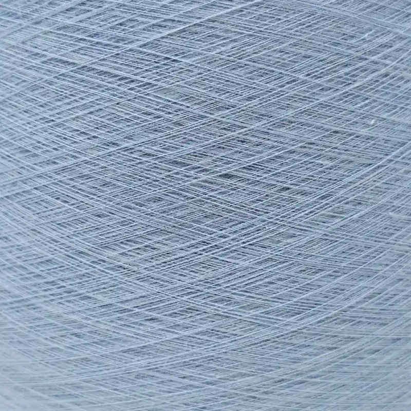 Cone sợi cotton mercerized 80S/2 màu xanh nhạt đặt nằm ngang, nhìn rõ lõi giấy.