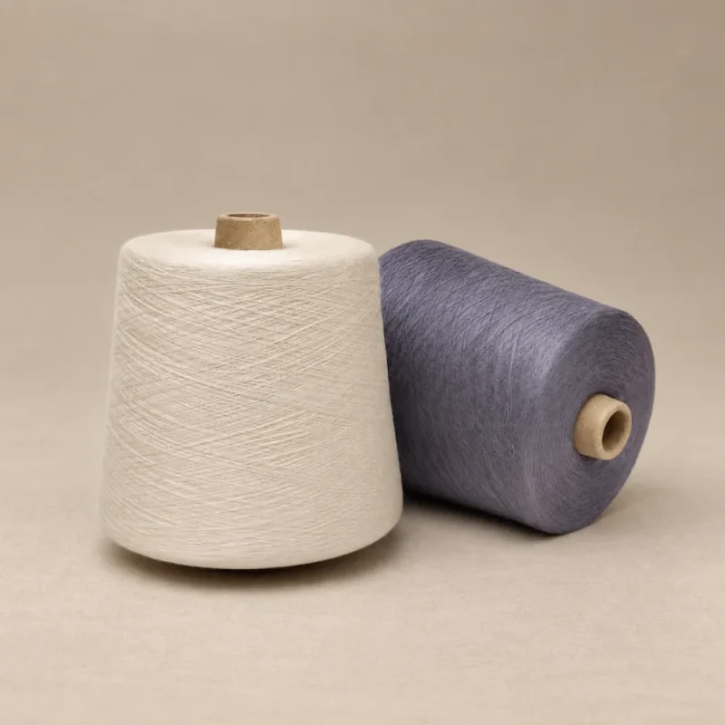 Cone sợi cotton mercerized màu trắng và xanh xám Hai cone sợi màu trắng và xanh xám đặt cạnh nhau