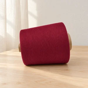 Cone sợi cotton màu đỏ rượu vang dạng ngang Cone sợi cotton màu đỏ rượu vang đặt nằm ngang trên mặt gỗ.