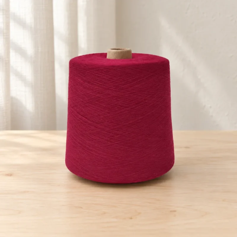 Cone sợi cotton nhuộm màu đỏ rượu vang Cone sợi cotton nhuộm màu đỏ rượu vang đặt trên mặt gỗ.