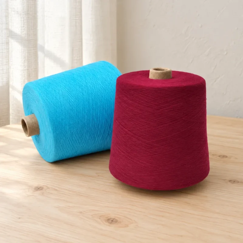 Cone sợi cotton màu xanh cyan và đỏ rượu vang Hai cone sợi cotton nhuộm màu xanh cyan và đỏ rượu vang đặt cạnh nhau.